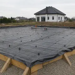 Fundament pod dom gotowy do zalania betonem. Widoczna folia pod chudziak, zbrojenie i elementy instalacji.