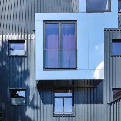 Nowoczesna elewacja frontowa z metalowymi panelami i geometrycznymi oknami.