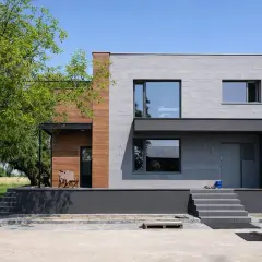 Nowoczesny dom kostka z betonową elewacją i drewnianymi akcentami. Elegancka, minimalistyczna bryła.