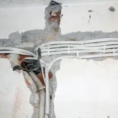 Widoczne przewody elektryczne w peszlach, częściowo odsłonięta puszka instalacyjna. Instalacja aluminiowa w trakcie prac.
