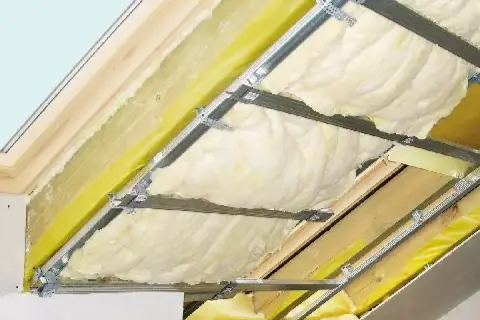 Montaż folii paroizolacyjnej na poddaszu. Widoczna wełna mineralna, profile aluminiowe i żółta folia.