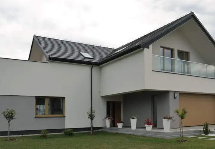Nowoczesny dom z dwuspadowym dachem i balkonem. Ocieplenie domu wzory tynków w odcieniach bieli i szarości.