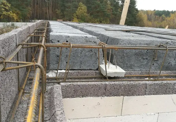 Budowa domu: betonowe pustaki i zbrojenie pod nadproże. Poduszka betonowa pod nadproże zapewnia stabilne podparcie.