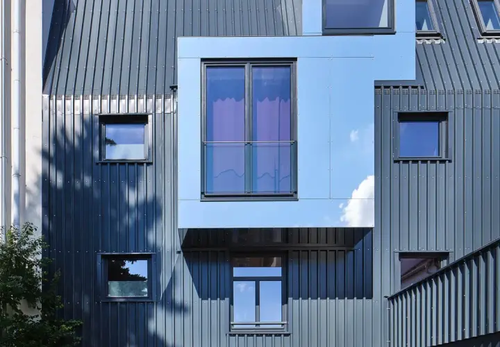 Nowoczesna elewacja frontowa z metalowymi panelami i geometrycznymi oknami.