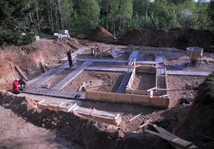 Prace budowlane w toku: trwa zalewanie fundamentów domu. Widać zbrojenie i szalunki.