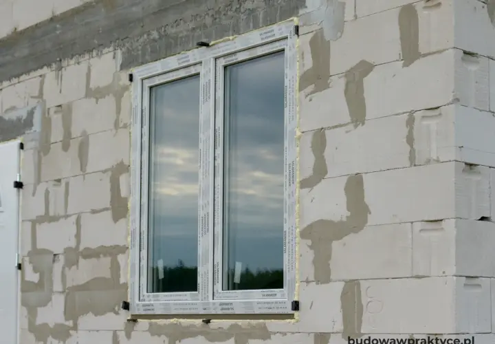 Okna w ścianie z bloczków betonowych, z widocznym pianką montażową. To maksymalny otwór bez nadproża, gotowy na dalsze prace budowlane.