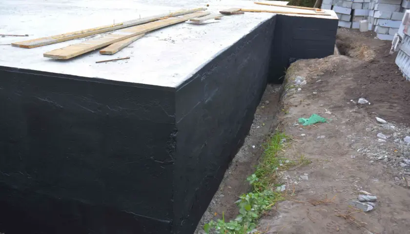 Zakończono hydroizolację piwnicy od zewnątrz. Czarna masa chroni fundamenty przed wilgocią.