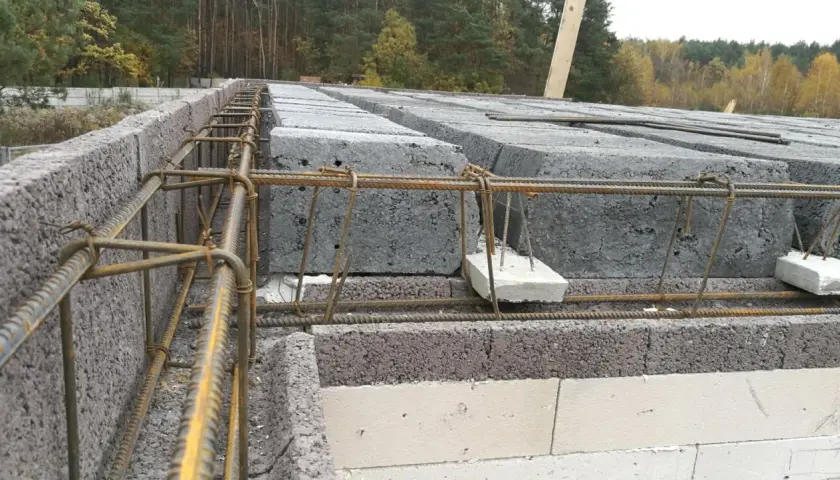 Budowa domu: betonowe pustaki i zbrojenie pod nadproże. Poduszka betonowa pod nadproże zapewnia stabilne podparcie.