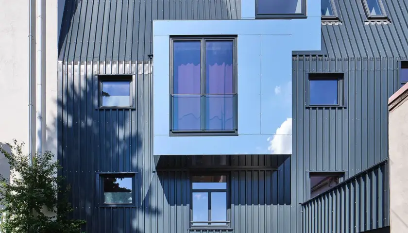 Nowoczesna elewacja frontowa z metalowymi panelami i geometrycznymi oknami.
