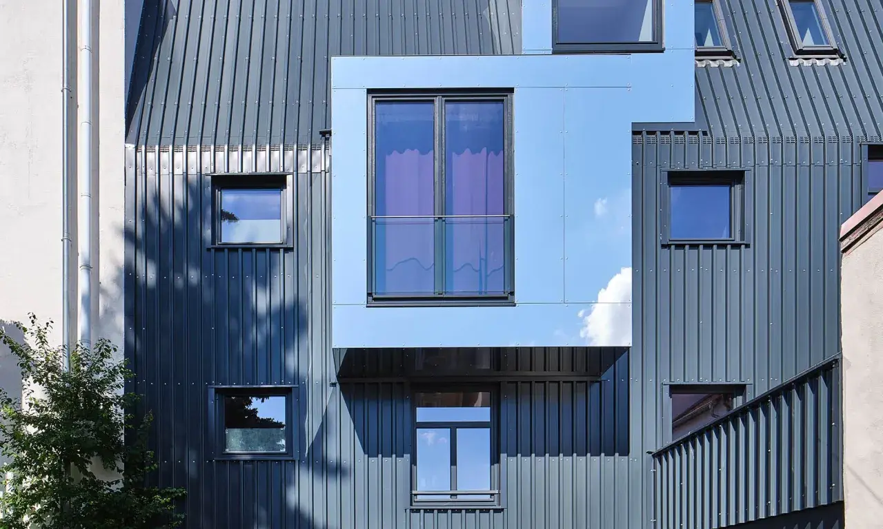 Nowoczesna elewacja frontowa z metalowymi panelami i geometrycznymi oknami.